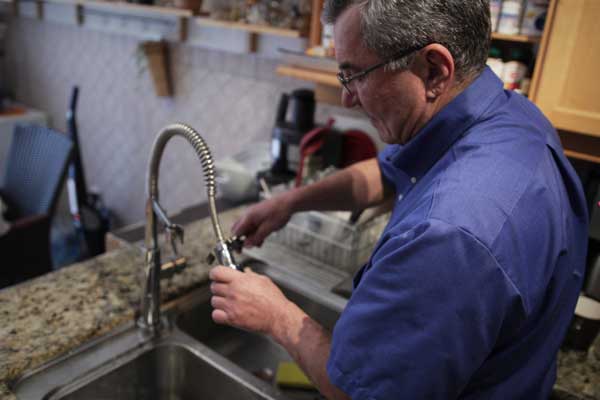 Master Plumber John Dima repairing a faucet in Toronto